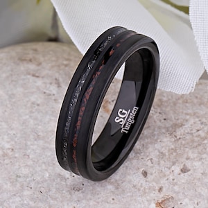 May include: Black tungsten ring with a brown and silver inlay. The ring has the words "SG Tungsten" engraved on the inside.