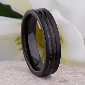 May include: Black tungsten carbide ring with a thin red and black inlay. The ring has a polished finish.