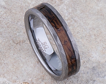 Op de afbeelding: Een zilveren ring van wolfraam met een bruine houten inlay en een gehammerde afwerking. De ring is gegraveerd met "SG Tungsten".