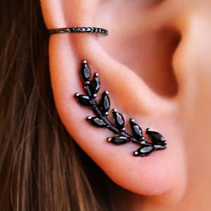 May include: Black ear cuff with a black diamond design and a black leaf ear climber with black diamond accents.