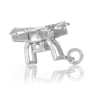 Könnte beinhalten: Silberner Anhänger in Form einer Drohne mit einem Ring zum Anbringen an einem Armband oder einer Halskette.