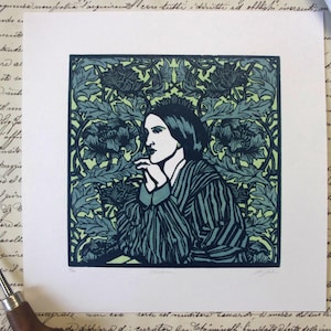 Peut inclure: Une estampe représentant une femme en tenue rayée, sur un fond floral dans des tons de bleu et de vert. L'œuvre est sur papier blanc, avec une écriture manuscrite en arrière-plan. Un outil et un tube de peinture sont également présents.