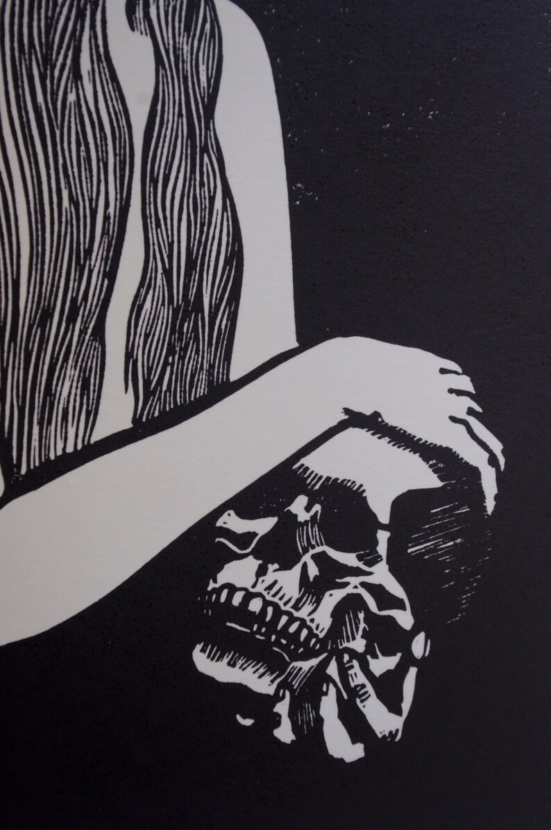 Puede incluir: Grabado en lin&oacute;leo en blanco y negro que presenta una calavera y una figura con pelo largo. La obra de arte tiene un dise&ntilde;o de alto contraste, con la calavera en primer plano y la forma de la figura en el fondo. El estilo recuerda a las xilograf&iacute;as.