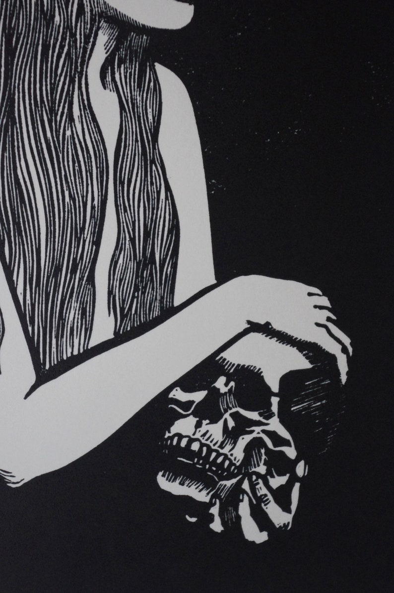 Puede incluir: Grabado en lin&oacute;leo en blanco y negro que representa una calavera sostenida por una persona. Se ven el brazo y el pelo largo de la persona, con los detalles y los dientes de la calavera claramente definidos. La obra tiene un alto contraste y un tema g&oacute;tico.