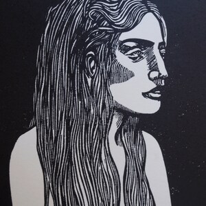 Puede incluir: Grabado en lin&oacute;leo en blanco y negro de una mujer de perfil. La obra de arte presenta una representaci&oacute;n detallada de una mujer con cabello largo y suelto. La imagen est&aacute; renderizada en un estilo de alto contraste, con l&iacute;neas y sombreados fuertes.
