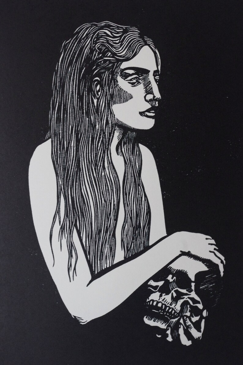Puede incluir: Grabado en lin&oacute;leo en blanco y negro de una mujer con cabello largo sosteniendo una calavera. La imagen de alto contraste presenta un fondo oscuro y una figura blanca, con un trabajo de l&iacute;neas detallado, evocando un tema g&oacute;tico.