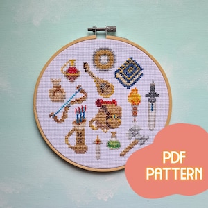 May include: A white embroidery hoop with a cross-stitch pattern of various fantasy role-playing game items, including a sword, a lute, a potion bottle, a bag of gold, a torch, and a quiver of arrows. The hoop is made of wood and has a natural finish. The text "PDF PATTERN" is written in orange on a pink background.