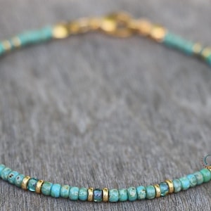 May include: A delicate turquoise and gold beaded necklace. The necklace is made with small, round turquoise beads and gold spacers.