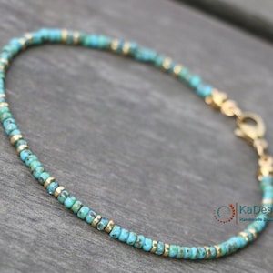 May include: A delicate turquoise and gold beaded bracelet with a lobster clasp closure. The bracelet is handmade and features small, round beads.
