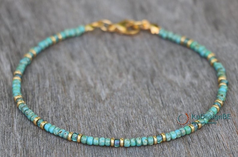 May include: A delicate turquoise and gold beaded bracelet with a simple clasp closure.