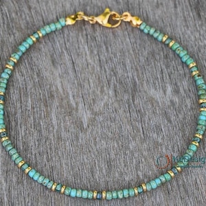 May include: A turquoise and gold beaded bracelet with a gold clasp.