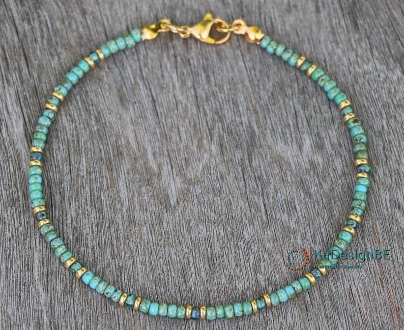May include: A turquoise and gold beaded bracelet with a gold clasp.