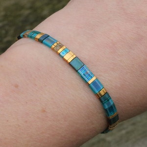 aqua flat tila bracelet on wrist. dainty bohemian bracelet; aqua and gold accents. Lightweight. stainless steel lobster clasp.