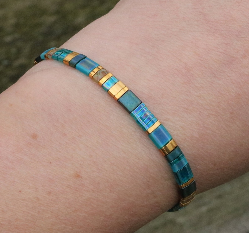 aqua flat tila bracelet on wrist. dainty bohemian bracelet; aqua and gold accents. Lightweight. stainless steel lobster clasp.