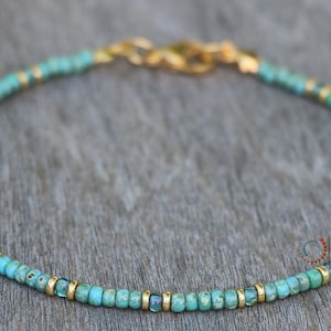 May include: A turquoise and gold beaded bracelet with a gold clasp.