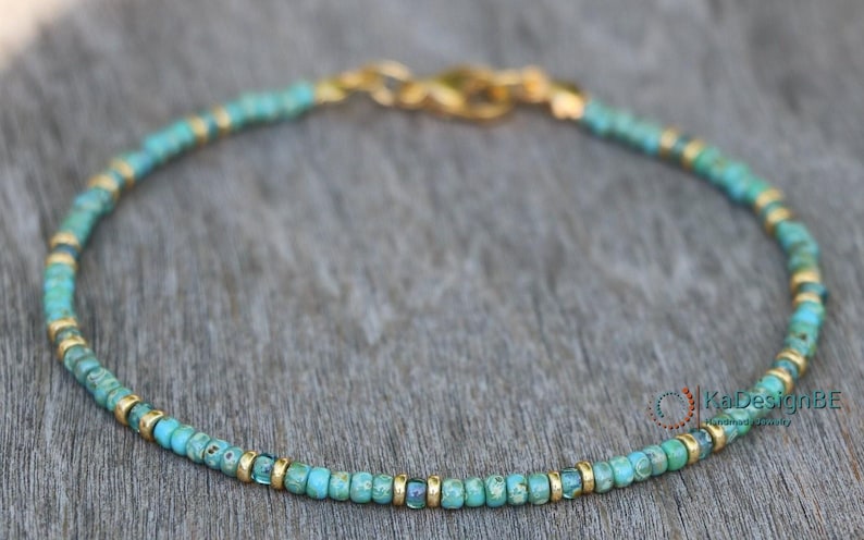 May include: A turquoise and gold beaded bracelet with a gold clasp.