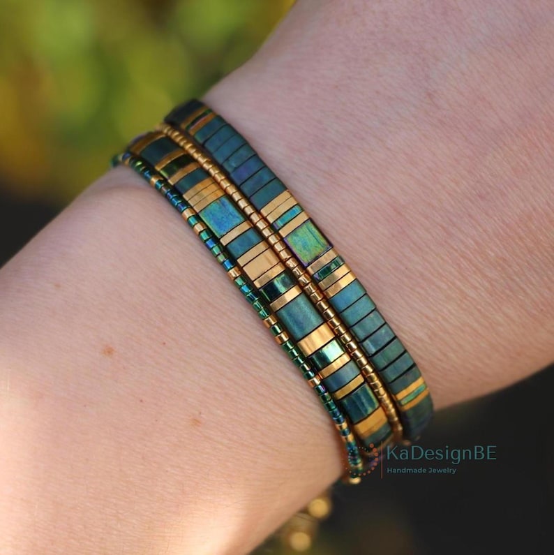Miyuki bracelet stack for women on a wrist. This 4bracelets set contains 2 tila bracelets and 2 tiny delica bracelets. All handmade with glass beads. It's a random pattern of greens and golds, contrasting color green-gold, and also matte and glossy. Minimalist, elegant dainty boho chic style.