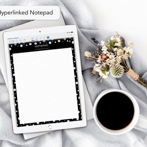 May include: A digital notepad on a tablet with a black border and white polka dots. The notepad displays lined paper and the word "NOTEPAD" at the top. A small bouquet of dried flowers and a cup of coffee are next to the tablet.