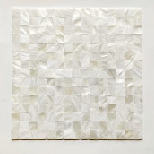 Könnte beinhalten: Quadratische Mosaikfliese aus zahlreichen kleinen, schillernden, cremeweißen Quadraten. Die Fliesen haben einen subtilen, perlmuttartigen Glanz, der eine strukturierte, optisch ansprechende Oberfläche erzeugt. Der Gesamteffekt ist ein klares, modernes Design für verschiedene Innenanwendungen.
