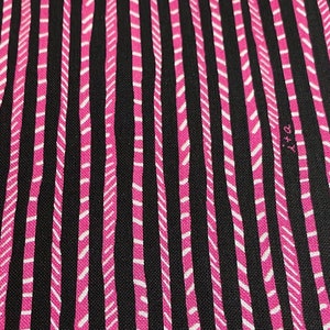 Könnte beinhalten: Schwarzer Stoff mit vertikalen rosa und weißen Streifen. Die Streifen haben ein Zickzackmuster.