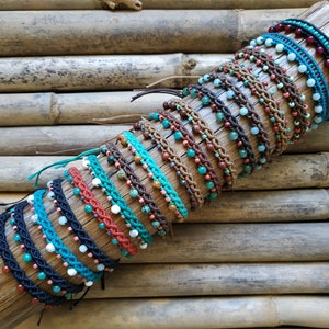 Puede incluir: Una colección de pulseras de cuentas coloridas con varios patrones y colores, incluyendo turquesa, marrón, rojo y negro. Las pulseras se muestran sobre una superficie de madera.