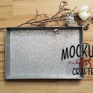 Może przedstawiać: Srebrna metalowa taca z fakturowaną powierzchnią. Taca ma czarne uchwyty i stoi na drewnianej powierzchni. Gałąź z białymi kwiatami magnolii leży na tacy. Tekst "Mockups for Crafters" jest napisany czarnym kolorem na białym tle.