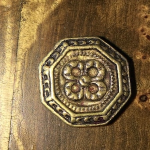 May include: A gold-toned octagonal cabinet knob with a decorative floral design.