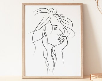 May include: A black and white line drawing of a woman's face with long hair, framed in a light wood frame.