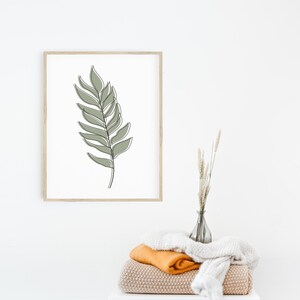 May include: A framed print of a minimalist line drawing of a green leaf on a white background.