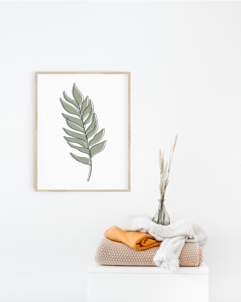 May include: A framed print of a minimalist line drawing of a green leaf on a white background.