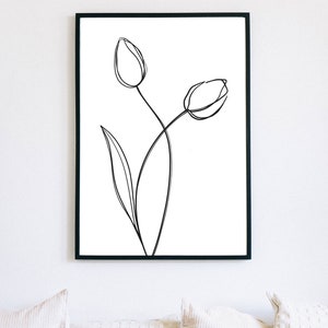 Puede incluir: Un dibujo en blanco y negro de dos tulipanes en un estilo simple y minimalista. El dibujo est&aacute; enmarcado en un marco negro y cuelga de una pared blanca.