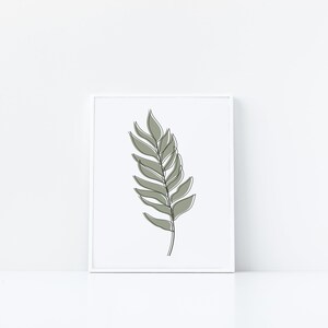 May include: A framed print of a minimalist line drawing of a green leaf on a white background.