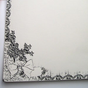 May include: A white envelope with a black and white floral design and a black ribbon closure. The envelope has two black buttons on the front.