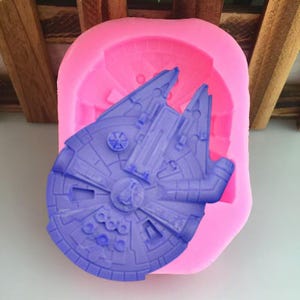 May include: Pink silicone mould for making a cake or other edible treat in the shape of the Millennium Falcon spaceship from Star Wars. The mould is empty and ready to be used.