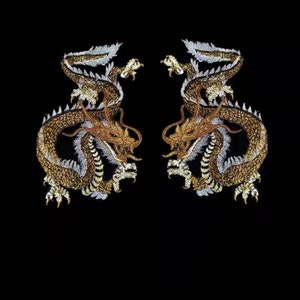 Può includere: Due toppe di drago ricamate in oro con accenti bianchi su uno sfondo nero.