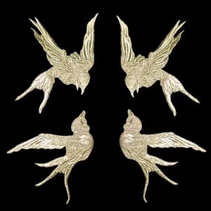 May include: Four gold glitter iron-on patches of swallows. Each patch is about 3 inches tall and 4 inches wide.