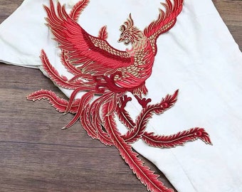 Puede incluir: Aplique bordado de fénix rojo con detalles dorados. El fénix se representa con las alas extendidas y una cola larga y fluida.
