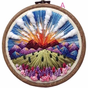May include: Embroidered hoop art featuring a colorful landscape with mountains, a sunset, and flowers. The hoop is made of wood and has a white background.