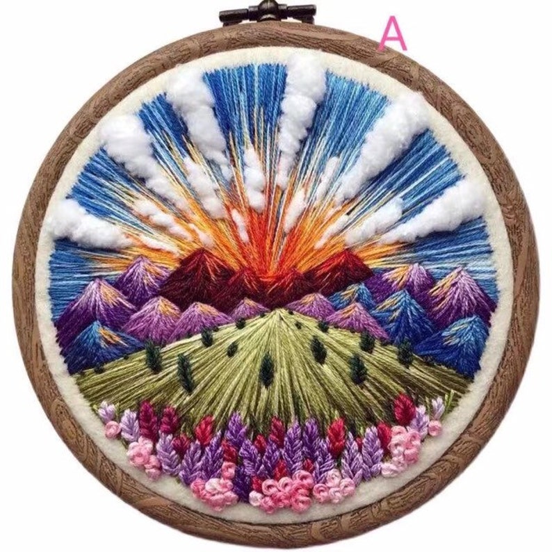 May include: Embroidered hoop art featuring a colorful landscape with mountains, a sunset, and flowers. The hoop is made of wood and has a white background.