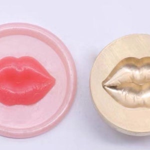 以下が含まれることがあります： ピンクの唇の形をした型と、唇の形をしたろうそくや石鹸を作るための金色の金属製の型のクローズアップ。