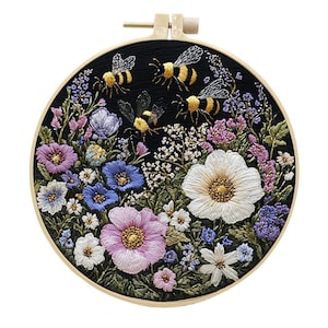 May include: An embroidered artwork in a wooden hoop, depicting a vibrant floral scene with bees. The design features a black backdrop with a variety of flowers in pink, blue, purple, and white. The bees are yellow and black. The hoop is approximately 20 cm in diameter.
