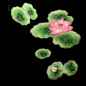 May include: Embroidered pink lotus flower with green leaves on a black background. The lotus flower is in bloom and has multiple petals. The leaves are detailed and have a realistic appearance.