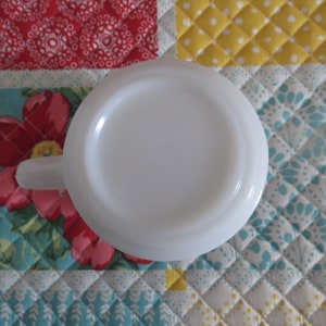 Pode incluir: Caneca de cer&acirc;mica branca com um interior branco liso. A caneca est&aacute; de cabe&ccedil;a para baixo, mostrando o fundo da caneca.