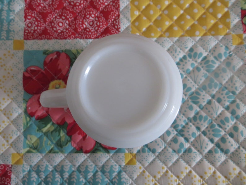 Pode incluir: Caneca de cer&acirc;mica branca com um interior branco liso. A caneca est&aacute; de cabe&ccedil;a para baixo, mostrando o fundo da caneca.