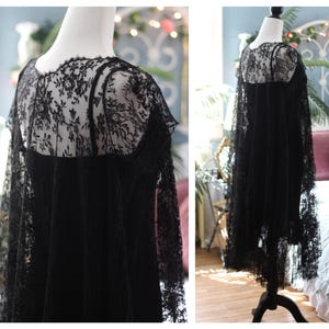 K&ouml;nnte beinhalten: Schwarzes Spitzenkleid mit floralem Muster. Das Kleid hat eine transparente Spitzenauflage auf dem Oberteil und den &Auml;rmeln mit einem einfarbigen schwarzen Untergrund. Das Kleid wird auf einer Schaufensterpuppe pr&auml;sentiert.