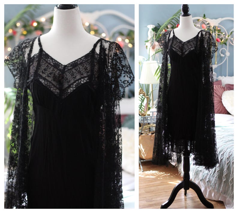 K&ouml;nnte beinhalten: Ein schwarzes Kleid im Vintage-Stil mit einer zarten Spitzenauflage und einem passenden Spitzenumhang. Das Kleid hat einen V-Ausschnitt und Spaghettitr&auml;ger. Der Umhang hat kurze &Auml;rmel und aufwendige Blumenmuster.