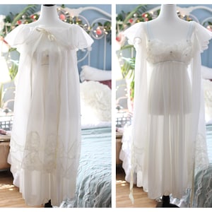 May include: Two white, sheer nightgowns on mannequins. One has a ruffled neckline and a long, flowing skirt with lace trim. The other has a lace bodice and delicate straps, with long, sheer sleeves. Both are displayed in a bedroom setting.