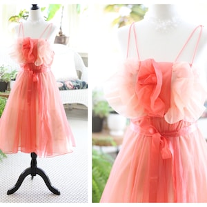 May include: A pink and peach ombre tulle dress with a ruffled bodice and a satin ribbon tie at the waist.