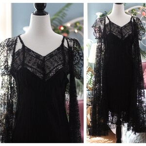 K&ouml;nnte beinhalten: Ein schwarzes Kleid mit V-Ausschnitt und Spaghettitr&auml;gern, &uuml;berzogen mit aufwendiger schwarzer Spitze. Das Kleid wird auf einer Schaufensterpuppe pr&auml;sentiert, mit einem passenden Spitzenschal &uuml;ber den Schultern.