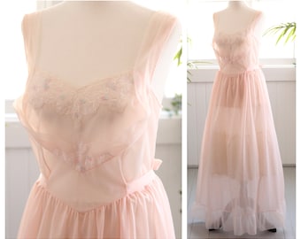 Op de afbeelding: Een delicate roze slipjurk met een kanten rand en een gerimpelde zoom. De jurk is doorschijnend en heeft een vintage stijl.
